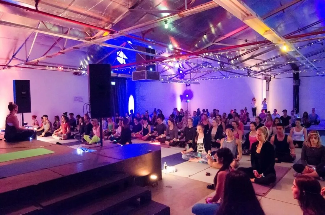 A large group seated in meditation in the warehouse space at Second Story Studios